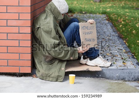 Poor homeless begging for money on a street - stock photo