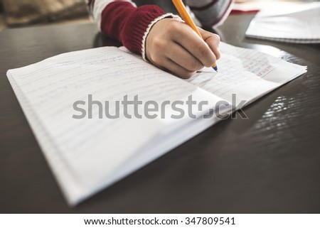 Child write in a notebook. Close up hand and pen