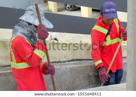 Muadzam Shah, Malaysia - March 22, 2018: Municipal workers "Alam Flora" uses sweepers and shovels to clean the garbage in the drain and put into the garbage bag.