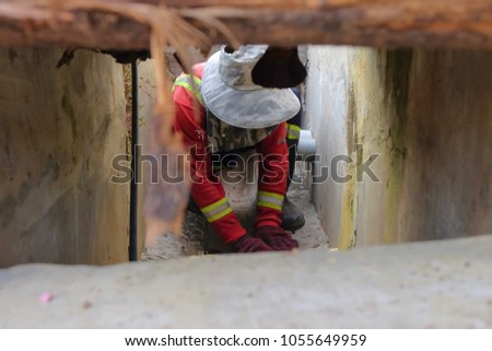 Muadzam Shah, Malaysia - March 22nd, 2018: Municipal worker "Alam Flora" uses sweepers and shovels to clean the garbage in the drain and put into the garbage bag.