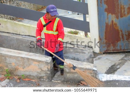 Muadzam Shah, Malaysia - March 22nd, 2018: Municipal worker "Alam Flora" uses sweepers and shovels to clean the garbage in the drain and put into the garbage bag.