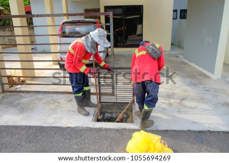 Muadzam Shah, Malaysia - March 22nd, 2018: Municipal workers "Alam Flora" uses sweepers and shovels to clean the garbage in the drain and put into the garbage bag.