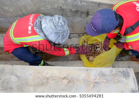 Muadzam Shah, Malaysia - March 22nd, 2018: Municipal workers "Alam Flora" uses sweepers and shovels to clean the garbage in the drain and put into the garbage bag.