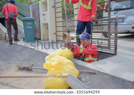 Muadzam Shah, Malaysia - March 22nd, 2018: Municipal workers "Alam Flora" uses sweepers and shovels to clean the garbage in the drain and put into the garbage bag.