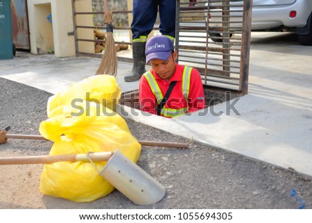 Muadzam Shah, Malaysia - March 22nd, 2018: Municipal workers "Alam Flora" uses sweepers and shovels to clean the garbage in the drain and put into the garbage bag.