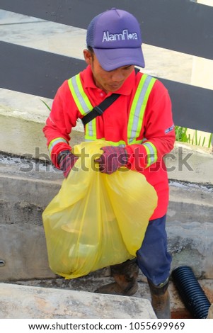 Muadzam Shah, Malaysia - March 22nd, 2018: Municipal worker "Alam Flora" uses sweepers and shovels to clean the garbage in the drain and put into the garbage bag.
