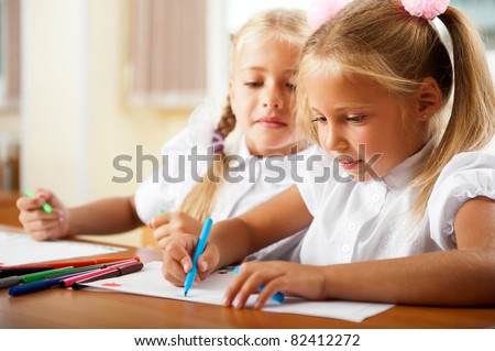 Little girls drawing pictures and writing letters to Santa Claus to get christmas gifts. Indoor at classroom