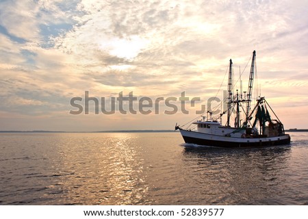 Fishing trawler on the water and dramatic clouds at sunrise