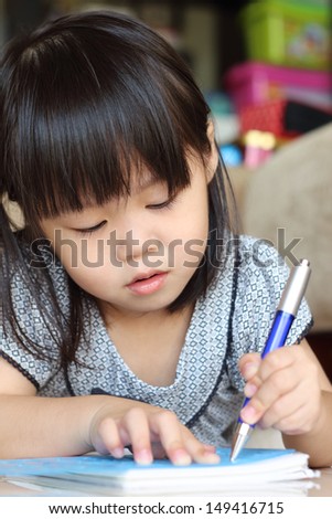 Girl lying on floor while writing using a stencil and pen