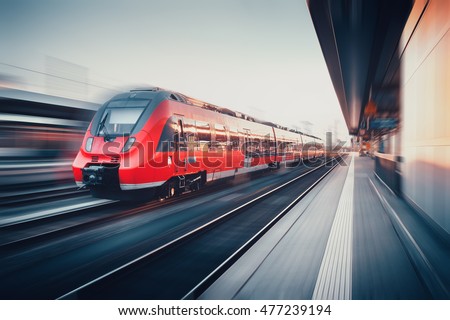 Beautiful railway station with modern high speed red commuter train with motion blur effect at sunset. Railroad. Vintage toning. Railroad travel background, tourism. Industrial