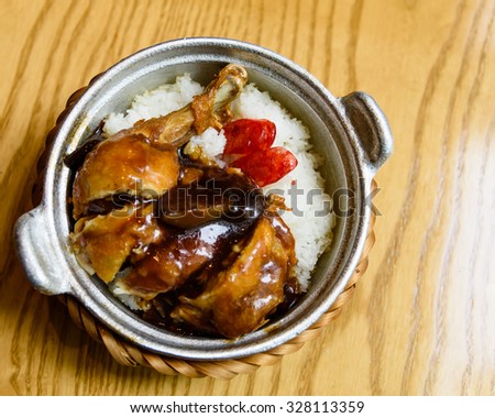 Top view of a delicious Vietnamese chicken rice pot made of rice, chicken, mushroom, sausage served in hot clay pot on wooden table background. Copy space