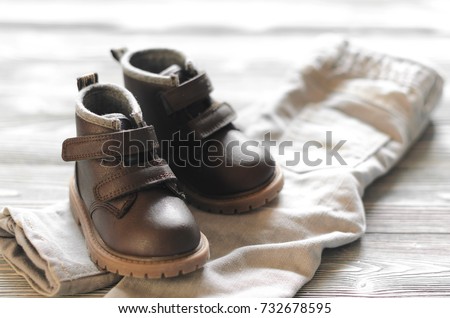 brown leather kids shoes and denim pants on wood backdrop