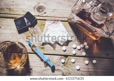 Overhead shot of hard drugs and alcohol on wooden table. Addiction concept