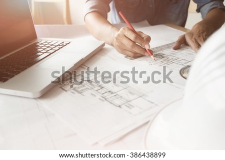 Close up of Architect sketching a construction project with laptop at work place.