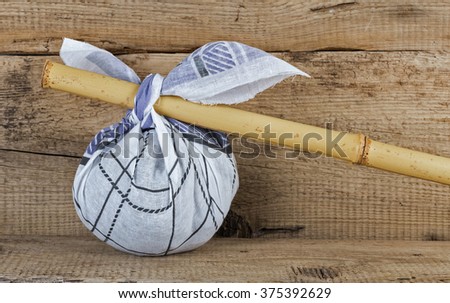 stock-photo-rural-knapsack-on-a-bamboo-pole-on-a-old-wooden-background-375392629.jpg