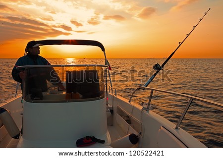 Fishing boat and fisherman in ocean at dawn
