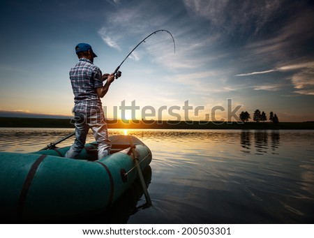 Mature man fishing from the boat on the pond at sunset