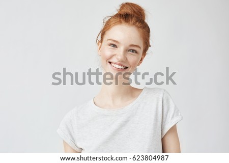 Headshot Portrait of happy ginger girl with freckles smiling looking at camera. White background.