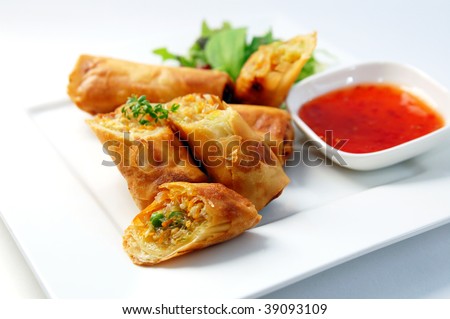 A plate of spring rolls with sweet chili dip sauce.