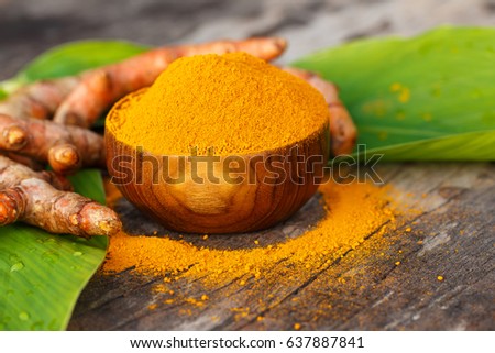 Turmeric powder in wooden bowls on old wooden table