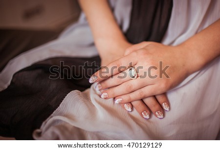 Woman's arm with a rich ring on the finger lie on her knees