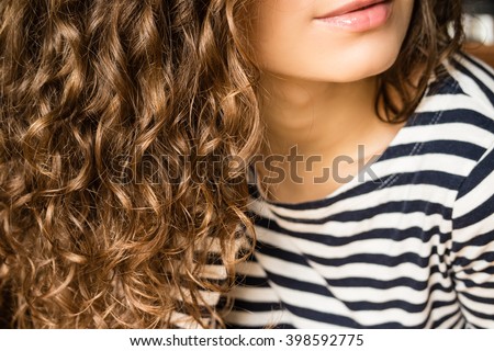 Girl with brown curly hair in a striped T-shirt close-up