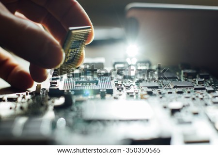 Technician plug in CPU microprocessor to motherboard socket. Workshop background