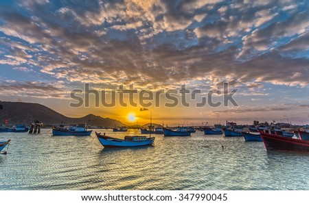 In Ninh Thuan, Vietnam - February 2nd, 2015: Sunrise over the pier with boat dock waiting to sail with yellow sky signaling a new day at sea beautiful start Ninh Thuan, Vietnam