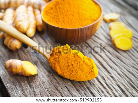 Turmeric powder in wooden spoon on old wooden table. herbal