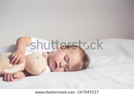 stock-photo-sleeping-baby-in-bed-holding-a-teddy-bear-567049537.jpg