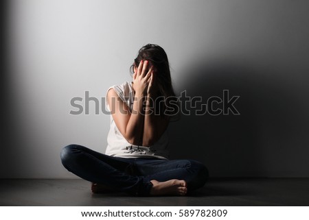 Teenager girl with depression sitting alone on the floor in the dark room