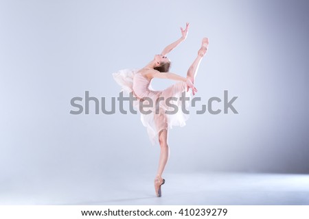 Young and incredibly beautiful ballerina is posing and dancing in a white studio full of light. The photo greatly reflects the incomparable beauty of a classical ballet art.
