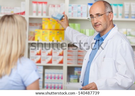 pharmacist talking to female client while taking medicine of the shelf