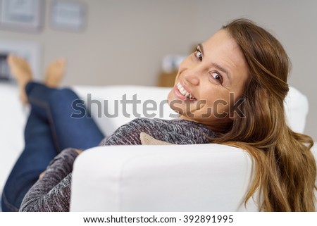 stock photo smiling happy woman unwinding at home lying barefoot on the sofa turning to look back and smile at 392891995