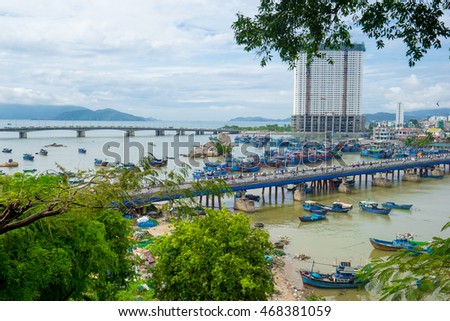 NHA TRANG, VIETNAM - JUNE 21, 2016: View of the bridge through the river with a set of fishing and transport boats. The high building and mountains in the distance