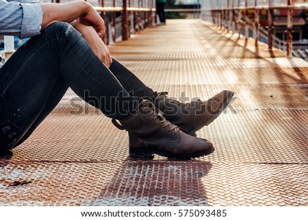 Men fashion in leather boots, Close up view on man's legs in black jeans and brown leather boots, Toned picture.