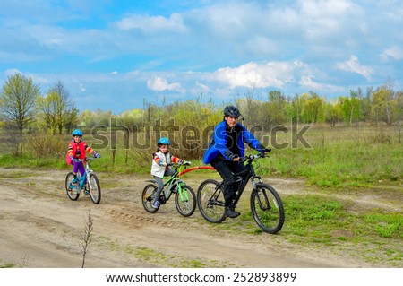 Happy family on bikes, father cycling with kids outdoors, active family sport