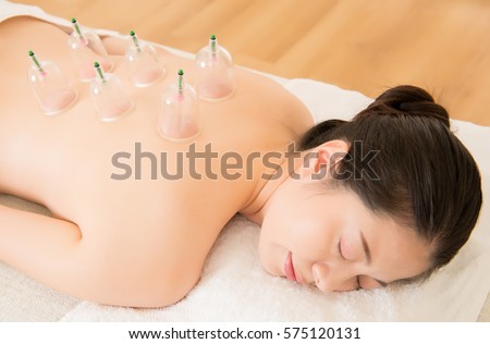 beautiful asian chinese woman laying on chest with cupping treatment on back and closed eyes in Chinese medicine clinic indoor. medical and health concept.