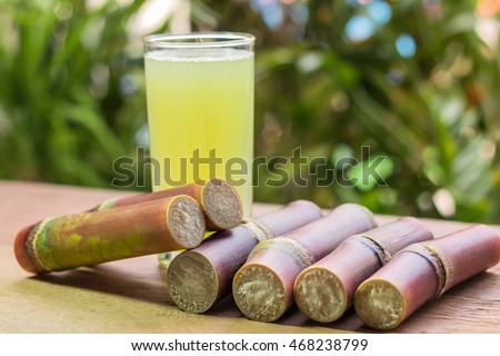 Sugarcane juice with piece of sugarcane on wooden background