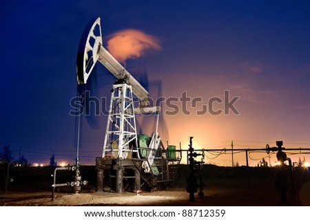 Oil pump-jack in action. Gas torches. Night view. Long exposure.
