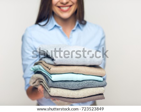Woman holding stack of folded clothes. Isolated laundry concept.