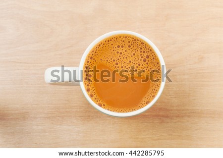 Hot milk tea in a white cup on wooden table
