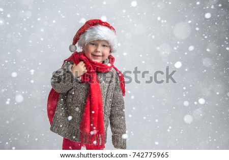 Happy boy in red xmas hat. Child with Xmas bag full of gifts and present. Buying christmas gifts - online shopping and delivery concept. Happy smiling boy with Santa costume. New Year and Christmas.