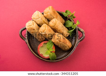 veg roll in brown ceramic bowl with mint leaf, isolated on red wooden background, top view