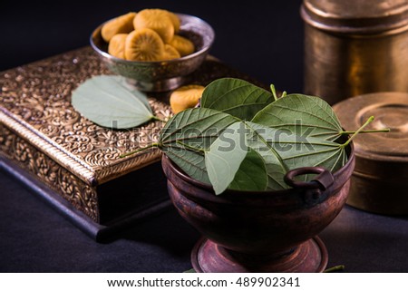indian festival dussehra or vijayadashmi or ayudh puja, showing apta leaf or Bauhinia racemosa with traditional indian sweets pedha in silver bowl