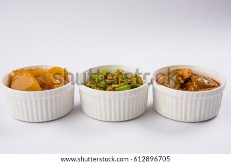 Group photograph of indian pickles like mango pickle , lemon pickle and green chilli pickle, sarved in white ceramic bowl, selective focus