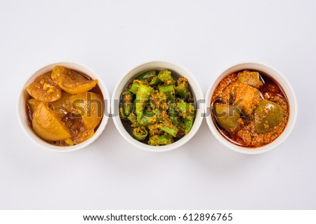 Group photograph of indian pickles like mango pickle , lemon pickle and green chilli pickle, sarved in white ceramic bowl, selective focus