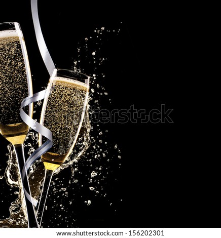 Glasses of champagne with splash, isolated on black background
