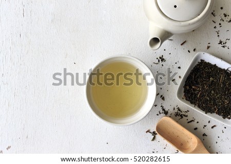 cup with green tea and teapot on white wooden table background. over light