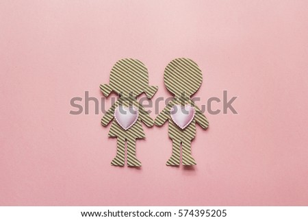 Cardboard silhouettes girl and boy with hearts on pink background. Valentine's Day background. Space for text. Top view.